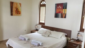 Un lit bien fait, avec une literie à motifs floraux, une tête de lit en bois et deux tables de chevet avec des lampes.