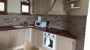 Une cuisine équipée d’un four à micro-ondes, d’un four traditionnel et de meubles de rangement en bois.