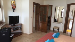 A hotel room with a bed, a TV, a desk with books, a suitcase, and a door leading to a bathroom. - 5 Star Luxury Villa - Large Private Pool - Spacious Rooms - Panoramic Sea Views (Balchik/Albena, Black Sea Coast)