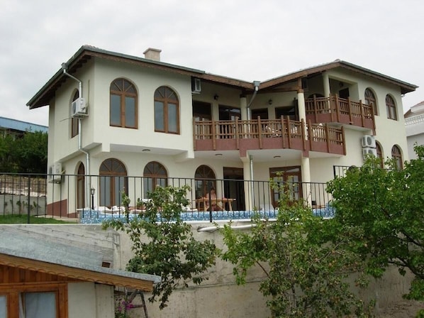 A two-story house with a balcony, a swimming pool, and a fenced yard.