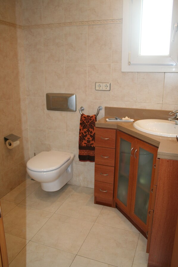 A bathroom with a toilet, sink, and cabinet.