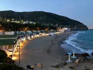 A beachside hotel with multiple rooms, a sandy beach, and a view of the ocean.