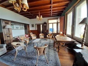 A room with a wooden ceiling, wicker furniture, a patterned rug, and a dining table. - house / villa - MORGAT (Crozon)