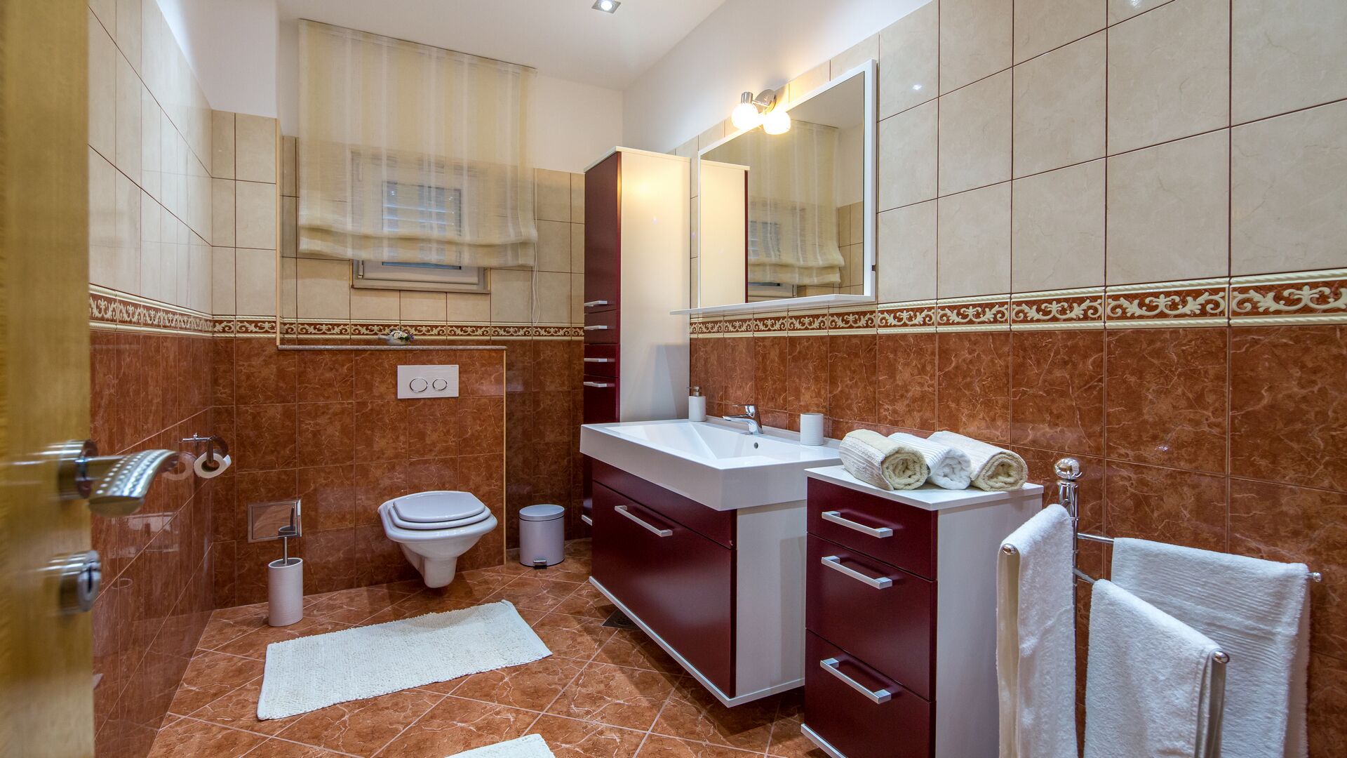 A bathroom with a marble floor, a white sink, a mirror, and a towel rack.