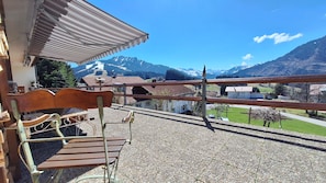 Un balcon avec un banc en bois, une rambarde en métal et une vue sur un paysage montagneux.