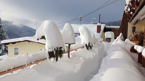 Schneeverdeckte Landschaft mit einem Gebäude und einem zäunchen.
