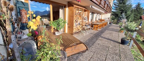 A wooden building with a wooden deck, outdoor seating, and a mountain view.