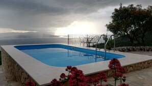 A rectangular swimming pool with a stone border and metal railings, surrounded by red flowers and a stone wall. - Villa Beloved near Baska voda, private pool (Bast)