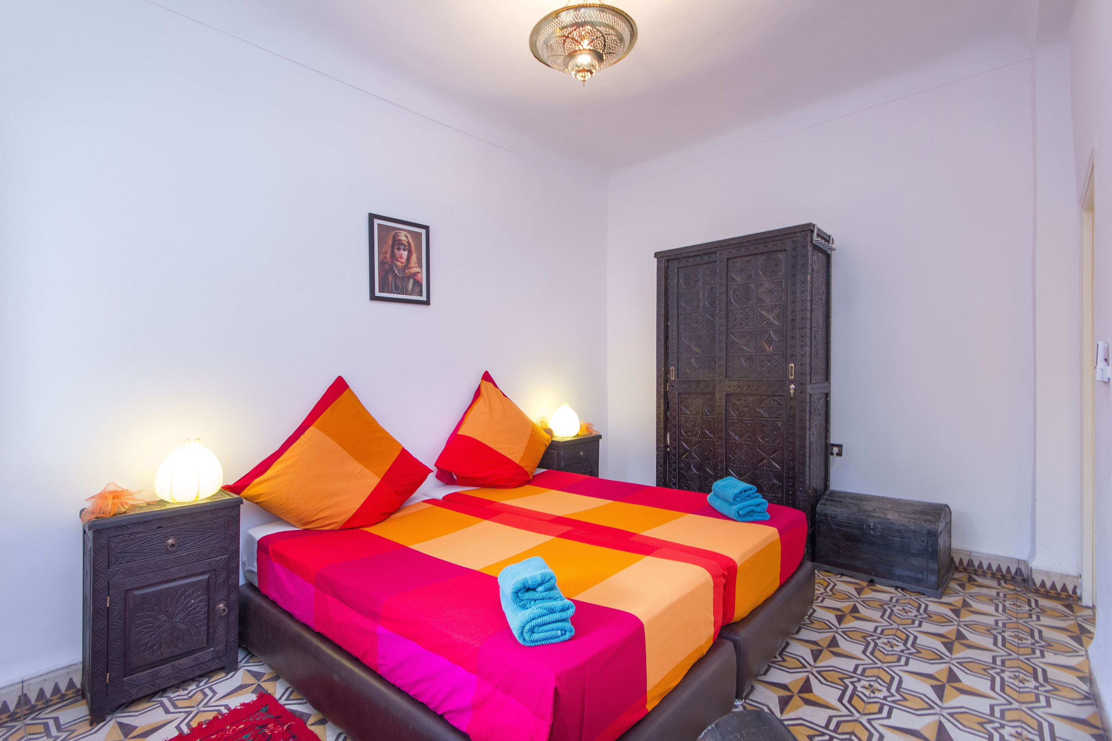 Une chambre à coucher comprenant un lit, des tables de chevet, une armoire et un revêtement de sol à motifs.