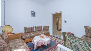 A room with a sofa set, a small round table, and a patterned rug. - Marrakech's Historic Heart – Palace Quarter in the Medina (Marrakesch)
