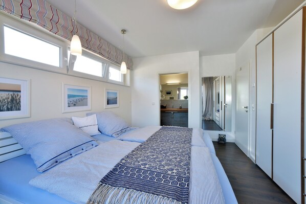 A bedroom with a large bed, a patterned throw, and a view of the bathroom through an open door. - Villa Seabird - A Top-Notch, Family-Friendly Villa with a Lake View (Trent)