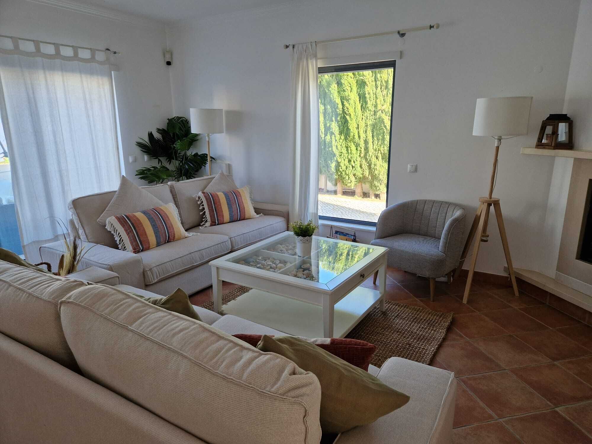 A living room with a sofa, armchair, coffee table, and a lamp.