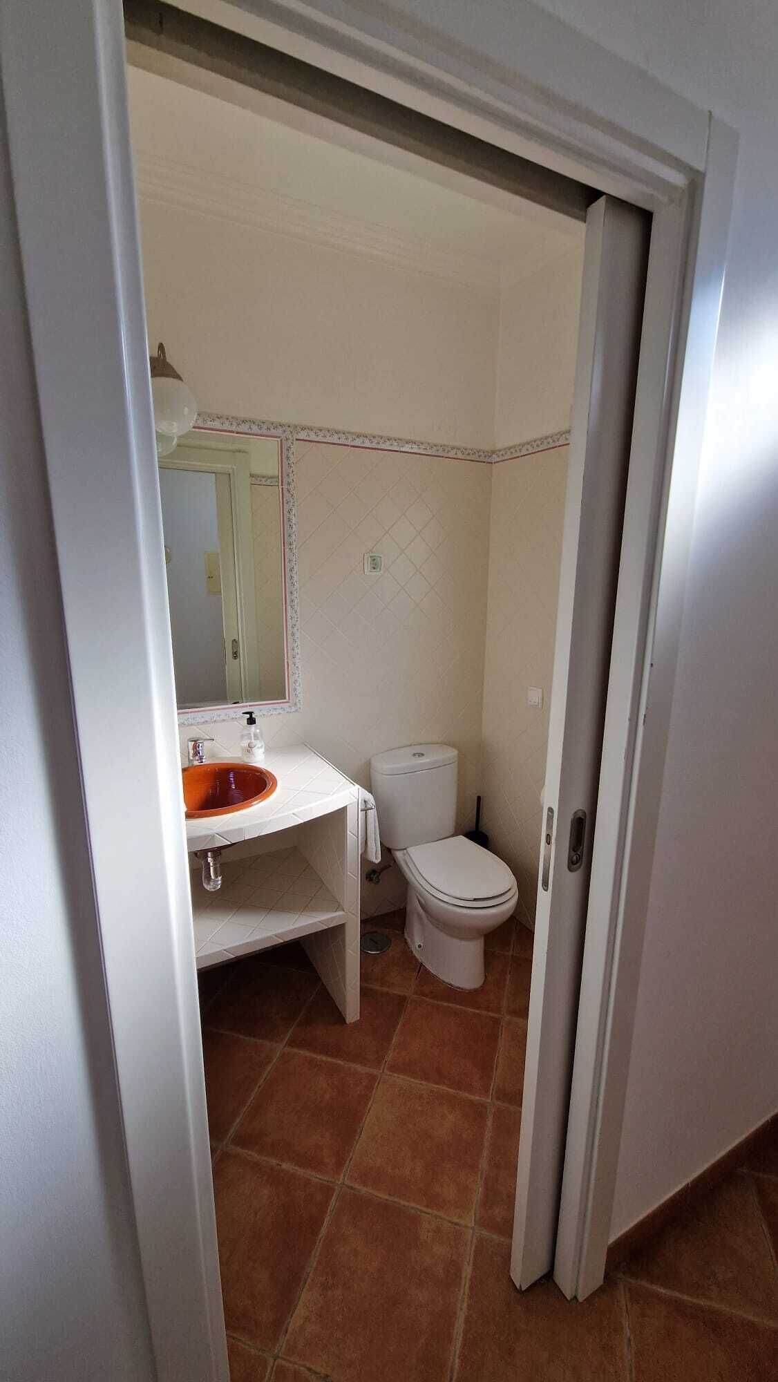 A bathroom with a white sink, a toilet, and a mirror.