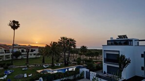 A resort with a pool, palm trees, and a sunset view. - Beachfront house, Manta Rota, Algarve (Private pool, Outdoor BBQ, Free Wifi, AC ..) (Vila Nova de Cacela)