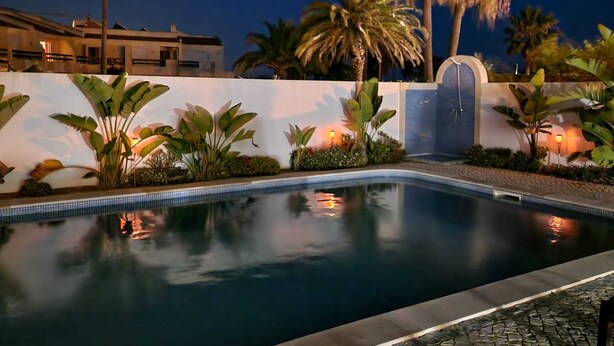 A swimming pool with a tiled edge, surrounded by tropical plants and palm trees. - Beachfront house, Manta Rota, Algarve (Private pool, Outdoor BBQ, Free Wifi, AC ..) (Vila Nova de Cacela)