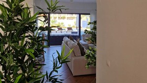 A spacious living area with a large arched doorway leading to a balcony, a wicker ceiling light, and several potted plants. - Beachfront house, Manta Rota, Algarve (Private pool, Outdoor BBQ, Free Wifi, AC ..) (Vila Nova de Cacela)