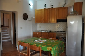 Une cuisine avec des meubles de rangement en bois, un réfrigérateur, une cuisinière et une table à manger avec des chaises.