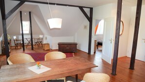 A spacious room with a wooden dining table, wicker chairs, and a hanging light fixture. - Apartment with flair in the south of Dresden (Plauen)