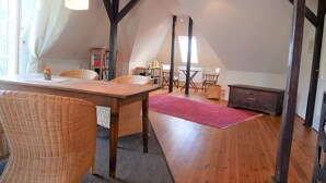 A room with a wooden table, wicker chairs, a red rug, and a dark wooden cabinet. - Apartment with flair in the south of Dresden (Plauen)