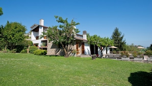 A two-story house with a stone facade, a tiled roof, and a well-maintained lawn.