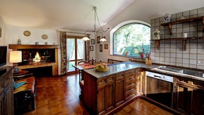 A spacious kitchen with a large island, wooden cabinets, a built-in oven, and a window overlooking greenery.