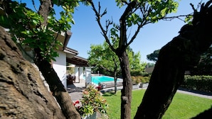 A residential property with a swimming pool, a patio, and a well-maintained lawn.
