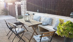 An outdoor seating area with a wooden table, cushioned chairs, and a bench with cushions.