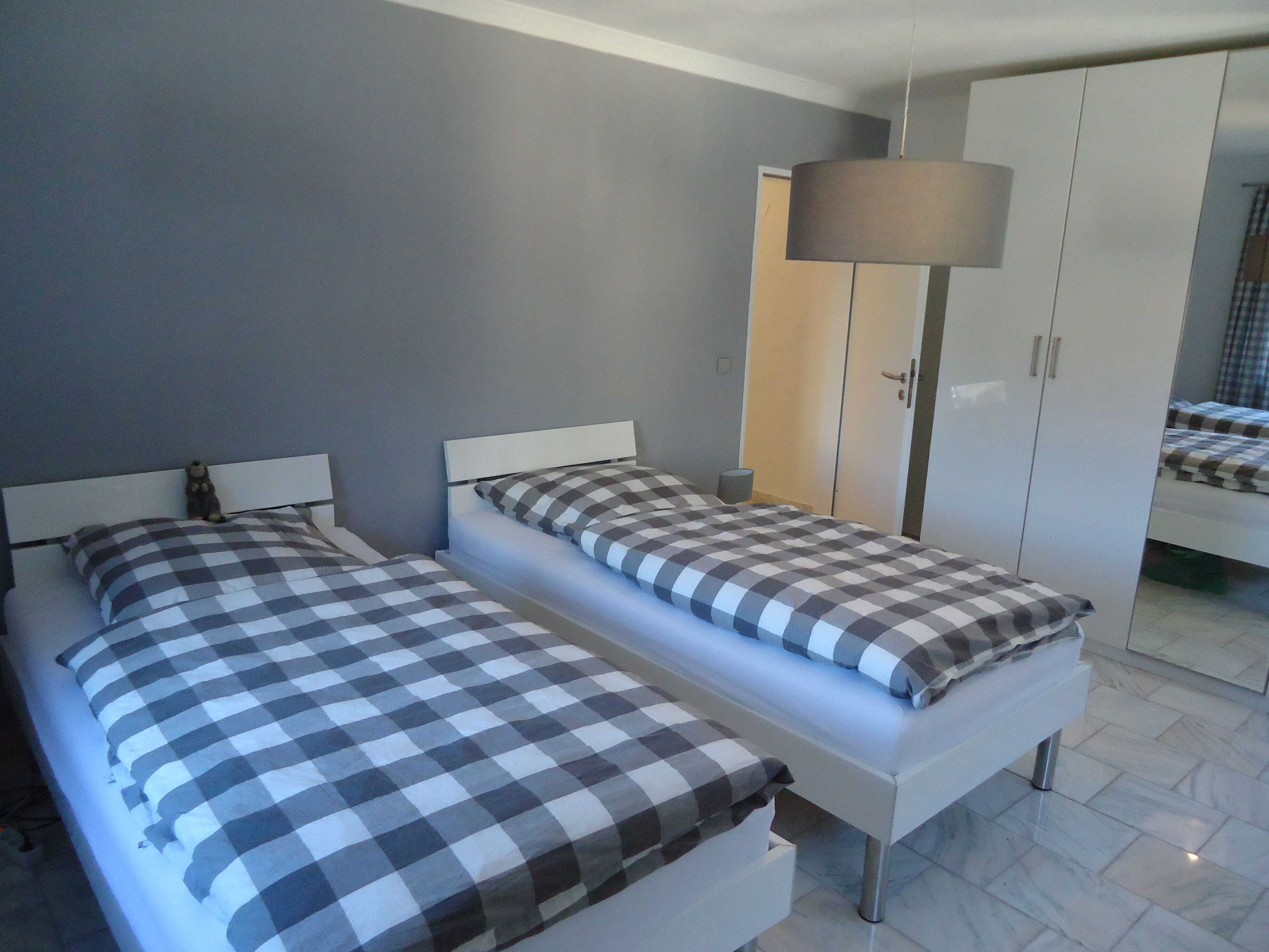 Une chambre avec deux lits, une armoire et une lampe sur pied.