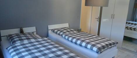 Une chambre avec deux lits, une armoire et une lampe sur pied.