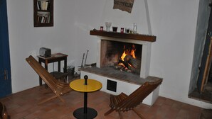 A cozy room with a fireplace, a bookshelf, and two wooden chairs.
