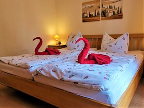 Une chambre d’hôtel avec un lit agrémenté d’une couvre-lit à motifs floraux et de deux serviettes rouges en forme de cygnes.