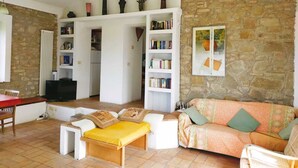 Un saló d'estar acollidor amb una paret de pedra, un sofà, una taula de centre i una prestatgeria plena de llibres.