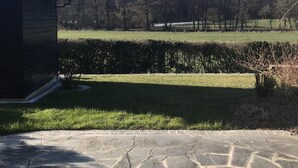 A stone patio leading to a grassy area with a wooden shed and a hedge. - Modern, quiet apartment in the countryside - in 30 minutes by train to Messe Frankfurt (Friedrichsdorf)