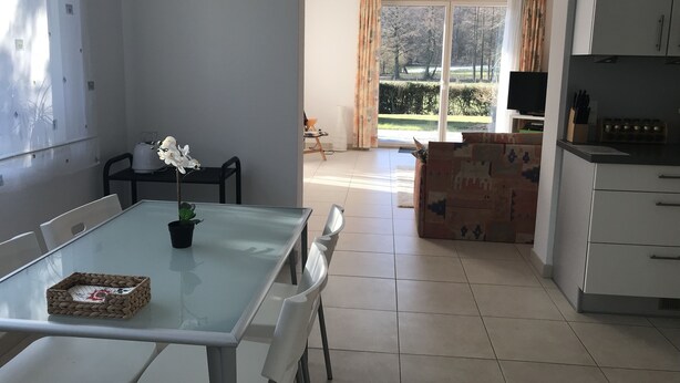 A modern kitchen with white cabinets, a dining table with chairs, and a view of a garden through a large window. - Modern, quiet apartment in the countryside - in 30 minutes by train to Messe Frankfurt (Friedrichsdorf)