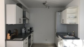 A modern kitchen with white cabinets, a coffee machine, and a sink. - Modern, quiet apartment in the countryside - in 30 minutes by train to Messe Frankfurt (Friedrichsdorf)