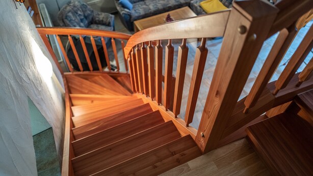 Een houten trap met een leuning en een houten vloer.