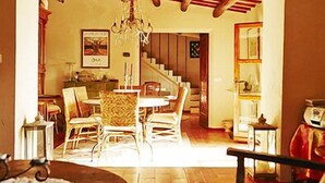 Uma sala de estar acolhedora com área de jantar, vigas de madeira no teto e um lustre.