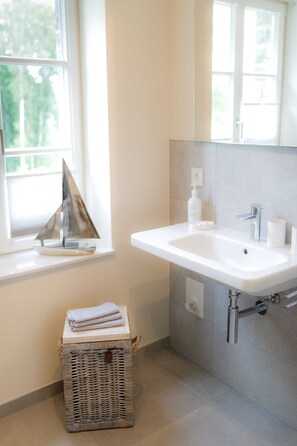 A bathroom with a white sink, a small window, a wicker basket, and a towel on top. - Apartment 1 - Edersee time out (Edertal)