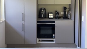 Une petite cuisine équipée comprenant un four encastré, une machine à café et un grille-pain.