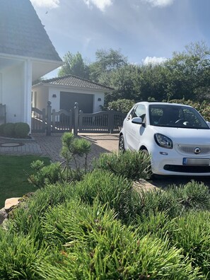 A white car parked in a driveway with a house in the background.
