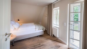 A bedroom with a bed, a bedside table, a lamp, and a window with curtains. - Apartment 7 - Edersee time out (Edertal)