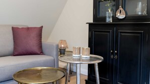 A living room with a grey sofa, a round metal table, and a black cabinet with glass doors. - Apartment 7 - Edersee time out (Edertal)