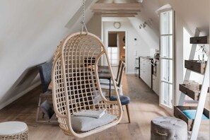 A cozy room with a hanging chair, a cushioned stool, and a wooden bench.