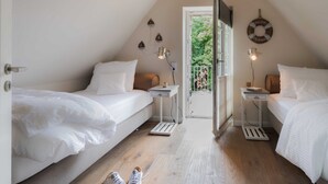 A cozy attic bedroom with two beds, a small table, and a door leading to a balcony. - Apartment 10 - Edersee time out (Edertal)