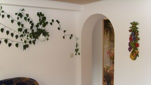 Un salón con un sofá estampado, una planta en forma de corazón montada en la pared y un adorno floral.
