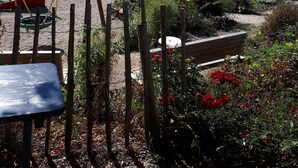 Un parque infantil con un tobogán y una estructura de madera, rodeado de vegetación y vistas a un lago.