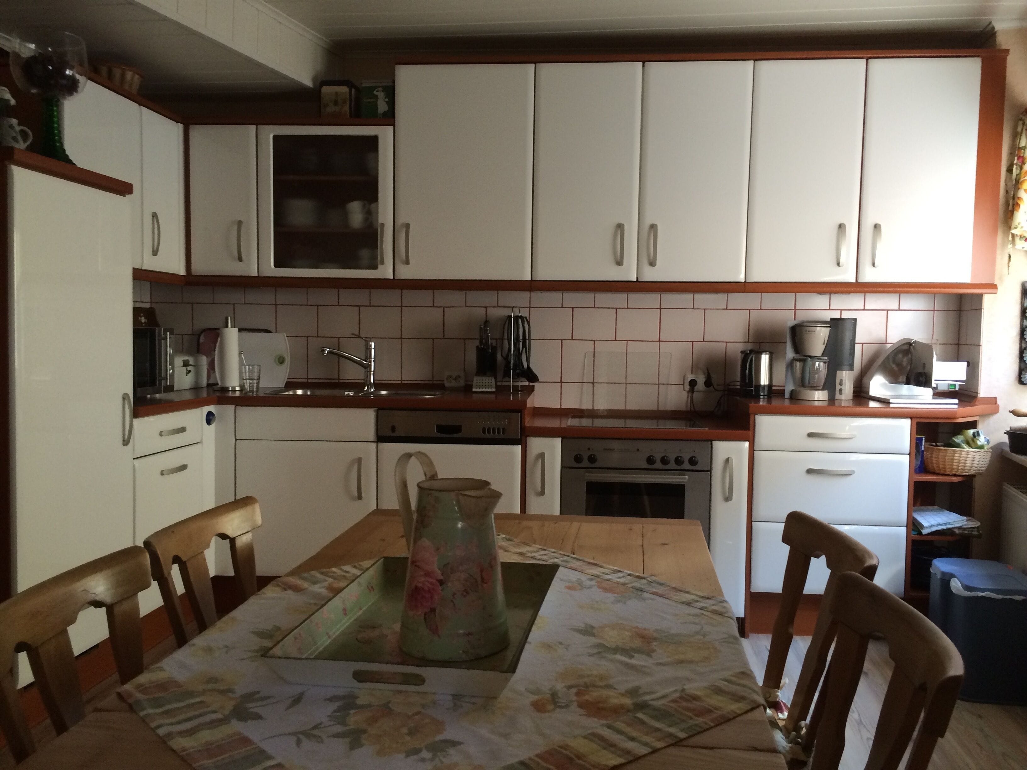 A kitchen with white cabinets, a wooden countertop, a sink, a stove, and a dining table with chairs.