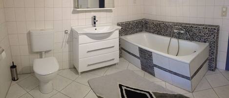 Een badkamer met toilet, wastafel en bad.