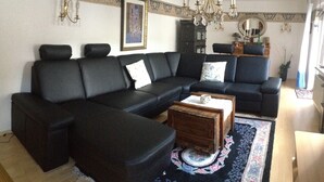Una sala de estar con un sofá modular negro, una mesa de centro de madera y una alfombra estampada.