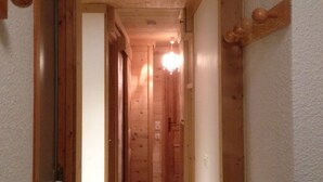 Un estrecho pasillo de madera con una puerta de madera a la izquierda y una pared de madera a la derecha.